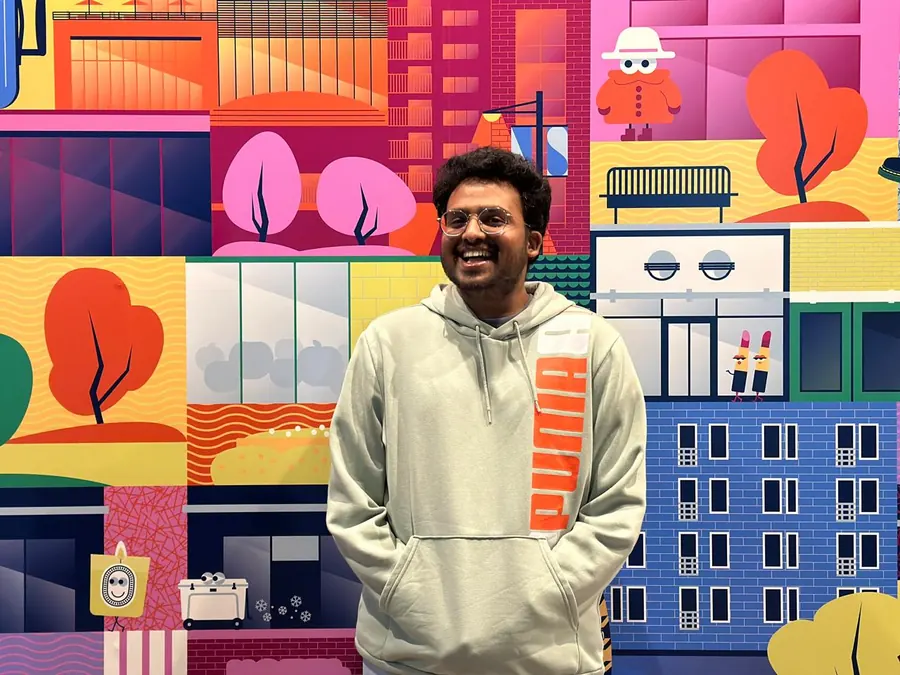 Amogh laughing in front of a colorful illustrated mural