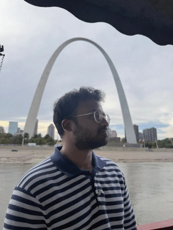 Amogh in profile by the river with the Gateway Arch behind him
